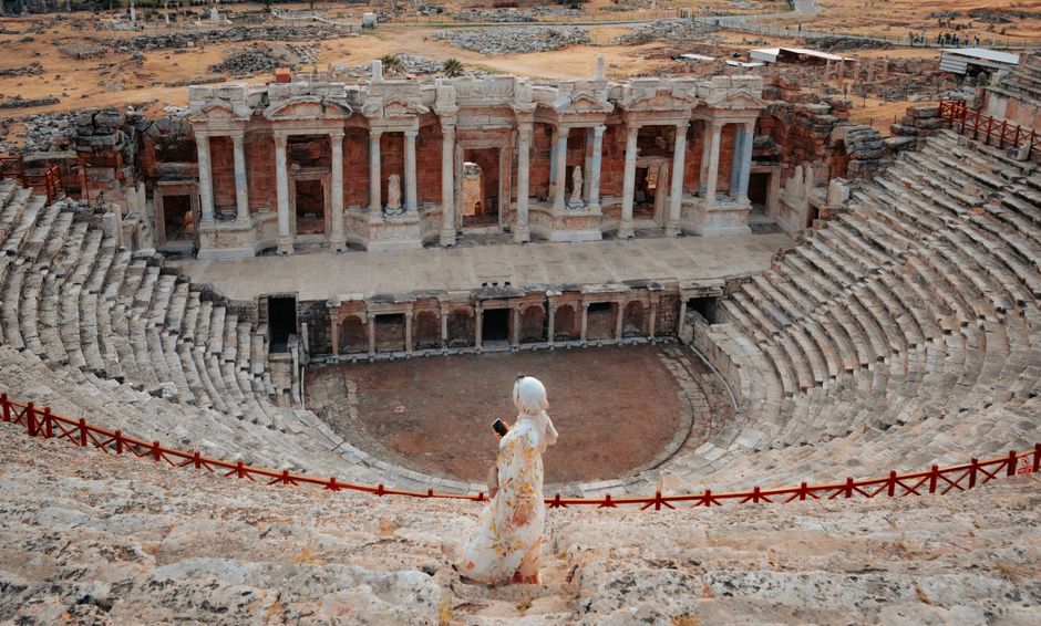 Woman admiring the grand architecture of the ancient Hierapolis theater in Pamukkale, Türkiye.