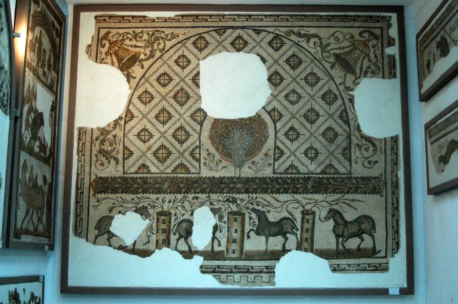 A detailed ancient mosaic featuring horses and a peacock with geometric designs.